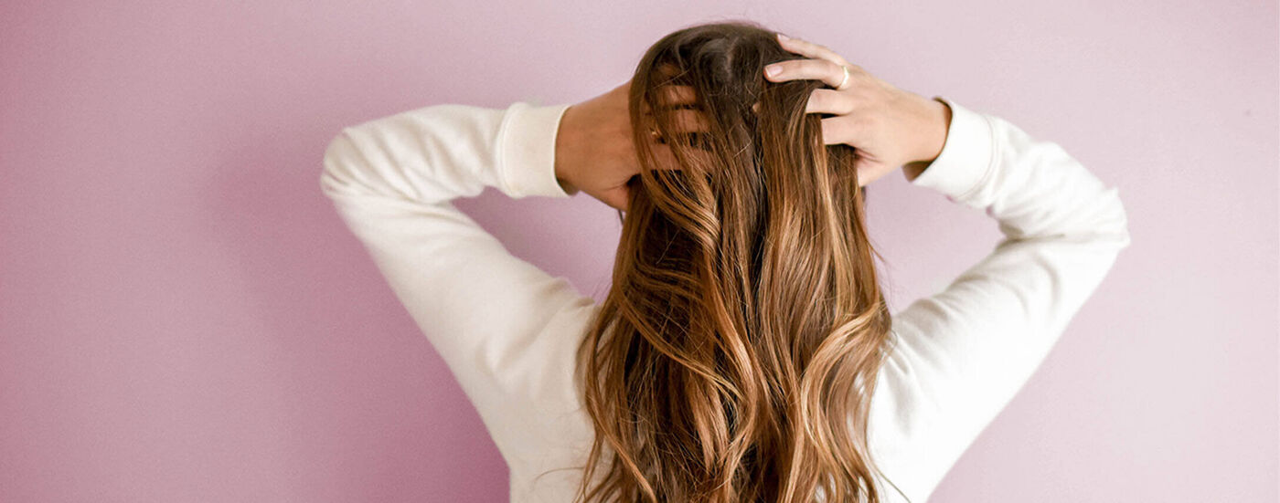 back of womans head running her fingers through her hair